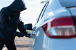 © inthasone - Close-up, Man dressed in a black holding screwdriver to break the lock and steal a vehicle on the road, Social destruction, Insurance, Car thief concept.