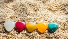 Beach Ball On Sand, Pills On White Background, Ball On The Beach, Green And Yellow Balls, Seven Color Chakra Crystal Stones On Sandy Beach, Chakra Energy Flow Healer Meditations