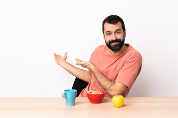 Wall Mural - Caucasian man having breakfast in a table extending hands to the side for inviting to come.