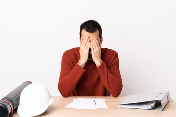 Wall Mural - Caucasian architect man with beard in a table covering eyes by hands.