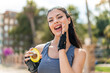 Young pretty sport woman holding an avocado at outdoors shouting with mouth wide open