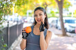 Young pretty sport woman holding an orange at outdoors shouting with mouth wide open
