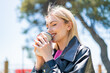 Young pretty blonde woman at outdoors holding a take away coffee with happy expression