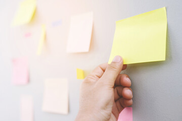 close up hand people business man  notes pad in the wall at meeting room. Sticky post note paper reminder schedule board. Colorful variety copy empty space. soft focus.