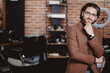 Portrait stylish man in jacket and glasses against background of barber chair in hairdresser. Concept client in barbershop