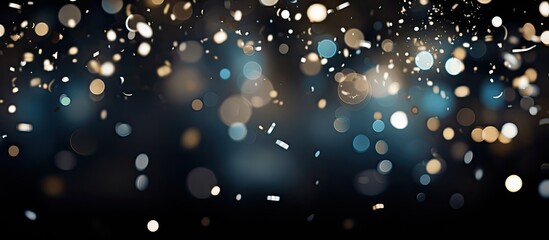A copy space image featuring shiny confetti creates silver bokeh spots against a black background