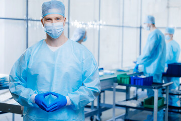 Portrait medical worker in med uniform on background industry automatic line machine for medicine production, blue toning