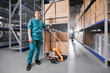 Caucasian industry man worker in blue uniform hold handle forklift in storage at medical products background of racks. Warehouse of med industry factory