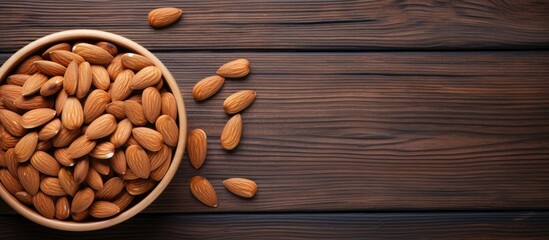 Wall Mural - A flat lay image shows almonds neatly arranged in a bowl while some are scattered on a wooden background There is plenty of copy space available in the image