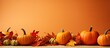 © HN Works - A fall scene with pumpkins and colorful leaves on an orange background providing copy space for images