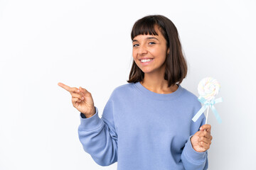 Wall Mural - Young mixed race woman holding a lollipop isolated on white background pointing finger to the side