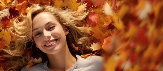 Poster - A happy young blonde girl lying on a pile of colorful autumn leaves with plenty of space for a picture. Creative banner. Copyspace image