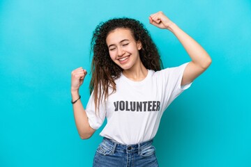 Wall Mural - Young Arab volunteer woman isolated on blue background celebrating a victory