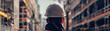 © artitwpd - A construction worker wearing a hard hat is standing on a building site, looking out at the city.