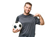 © luismolinero - Young handsome blonde man over isolated chroma key background with soccer ball and proud of himself