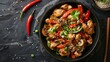 © Suleyman - Stir-fried turkey with peppers, mushrooms, chives, and sesame seeds in a skillet. An Asian-style dish on a black stone kitchen counter, seen from above.