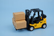 Forklift track with three carton boxes on blue background close-up.