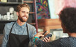 © peopleimages.com - Barista, woman and phone for payment in coffee shop with service, help or happy for easy transaction. People, machine and scan smartphone with fintech, bills and banking app with waiter in cafeteria