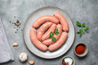 Raw homemade sausages in a plate on a gray concrete background. Top view, flat lay.