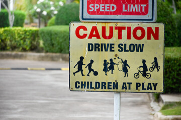 sign caution speed limit drive slow children at play on yellow background at park in evening sunset,