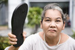 Angry old senior woman holding slipper and being ready to slap or hurt you, concept image of violence, aggression, physical assault, anger management