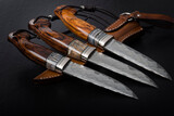 Fototapeta Storczyk - Three handmade hunting knives on a black background.