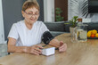 Senior caucasian woman measures her blood pressure at home using a tonometer. Everyday health checkup