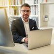 © peopleimages.com - Laptop, desk and portrait of business man in office for working online, research and website. Investment banker, professional advisor and person on computer for career, financial consulting and job