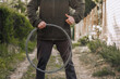 A strong man, a professional repairman, mechanic in uniform holds a round roll of metal wire in his hands outdoors, showing like, thumbs up. Close-up photography, industry concept.