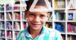 Image of triangles over close up of smiling biracial boy standing in library room