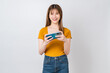 Excited young Asian woman playing games with smartphone on white background.
