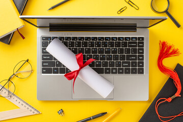yellow background shows a laptop with a rolled diploma tied with red ribbon, surrounded by education