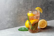 Iced tea with mint and lemon on a grey background.