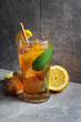 Iced tea with mint, ginger, and lemon on a grey background.
