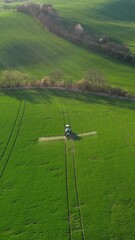 Wall Mural - aerial view of amazing green wavy hills with agricultural fields in spring. tractor crop sprayer on 