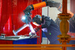 Man welder at work. Production of steel pipes. Welder works in factory. Welding machine in hands of man. Equipment for smoke extraction in production. Welder in mask protecting his face