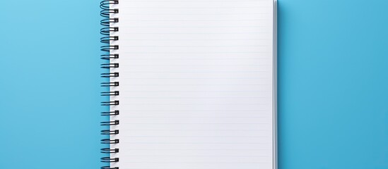 A close up view of a notebook placed on a blue background with ample space for adding images or text