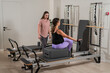 © Михаил Решетников - Caucasian pregnant woman doing Pilates exercises on a reformer machine with an individual trainer.