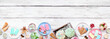 Cool summer food bottom border. Group of ice cream, popsicles and frozen treats. Pastel colors. Top down view on a white wood banner background.