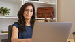 © Krakenimages.com - Professional hispanic mature woman working in an office interior with laptop, glasses and elegant attire.