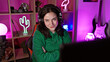 © Krakenimages.com - A young caucasian woman with folded arms wearing headphones in a neon-lit gaming room at night