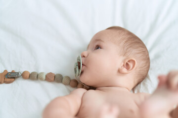 Sticker - Adorable toddler lying on bed sucking pacifier at bedroom