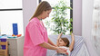© Krakenimages.com - Pediatrician in pink scrubs comforting girl patient lying on exam table in a bright clinic room