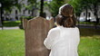 © Krakenimages.com - Beautiful young hispanic woman praying and mourning by tombstone at graveyard