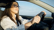 © Krakenimages.com - Young beautiful hispanic woman driving a car smiling wearing glasses on the road