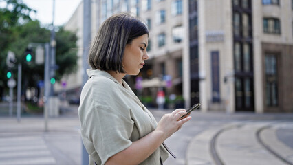 Wall Mural - Young beautiful hispanic woman using smartphone walking at cafeteria