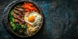 Bowl of bibimbap, a Korean rice dish topped with assorted vegetables, marinated beef, a fried egg, and spicy gochujang sauce, served in a traditional stone bowl
