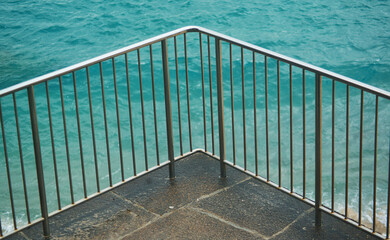 Metal embankment railings against the backdrop of green sea water.