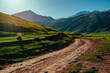 Picturesque mountain valley with dirt road at sunset