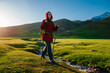Young woman tourist walks along stream in picturesque mountain valley on a sunny day